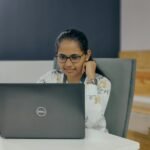 a woman sitting in front of a laptop computer